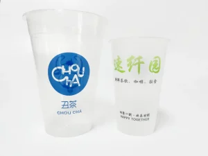 Two branded plastic beverage cups on display. Left: Transparent cup with a blue circular “Chou Cha” logo in stylized and standard fonts. Right: Frosted cup featuring green Chinese characters and the phrase “Happy Together” in English.