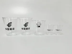 A collection of disposable plastic cups with single-color logos and text, printed using the AP-600-8 Automatic Cup Printing Machine. Features precise photoelectric sensor positioning and LED UV curing for durable prints on curved disposable surfaces.