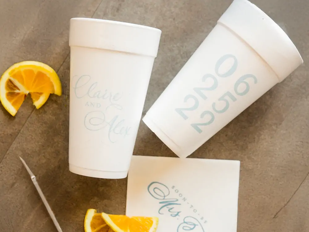 A stack of white styrofoam cups, some blank and some with a simple, clean design, illustrating the brand visibility and professional appearance benefits of printing on styrofoam.